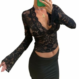 Person wearing a black lace top with a skirt holding a phone.