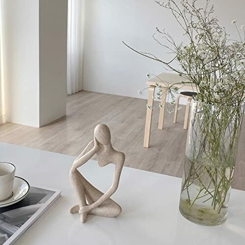 Minimalist room with abstract sculpture and flowers on table.