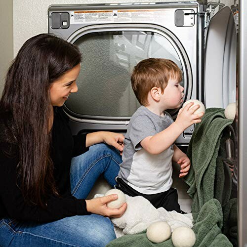 Mother and child placing wool dryer balls in a laundry dryer.