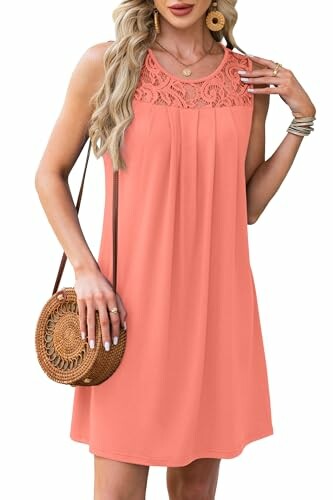 Woman wearing sleeveless coral dress with lace detailing and holding a round woven bag.