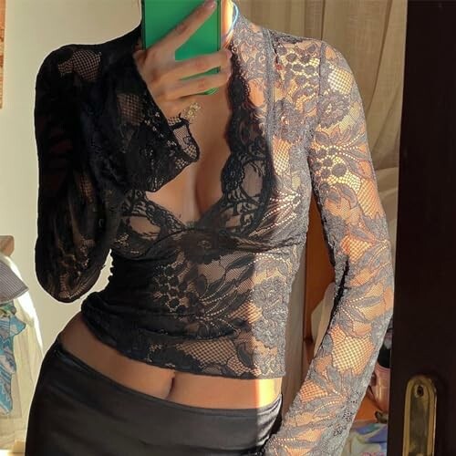 Person wearing a black lace top taking a mirror selfie.