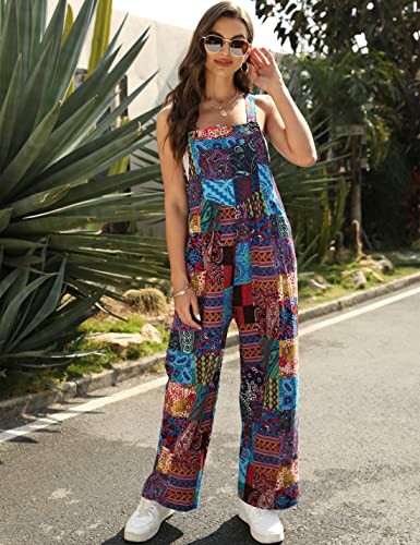 Woman in colorful patchwork jumpsuit and sunglasses standing on a street