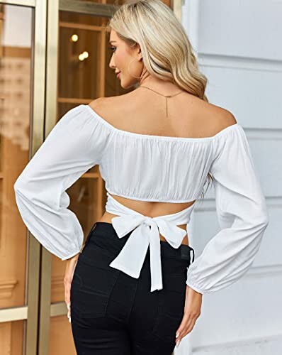 Woman wearing a white off-shoulder top with black pants.