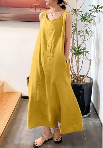 Woman in a yellow sleeveless dress standing indoors.